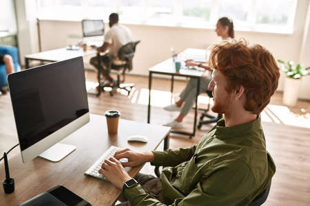 European man typing on laptop while working
