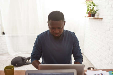 Black man working on laptop at home workspace