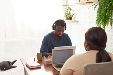 Black man and girl working on laptops at home