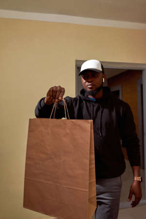 Black male courier holding paper bag with orderの写真素材