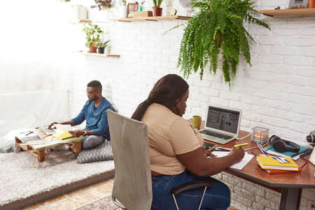Woman draw on paper while blurred man use laptop