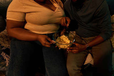 Partial of couple eat chips and watch TV or movie