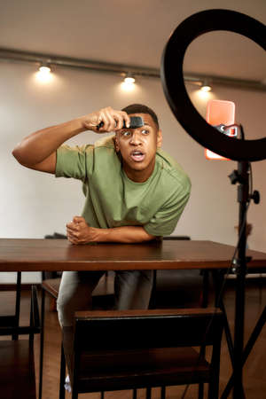 Man shaving eyebrow with electric razor for video