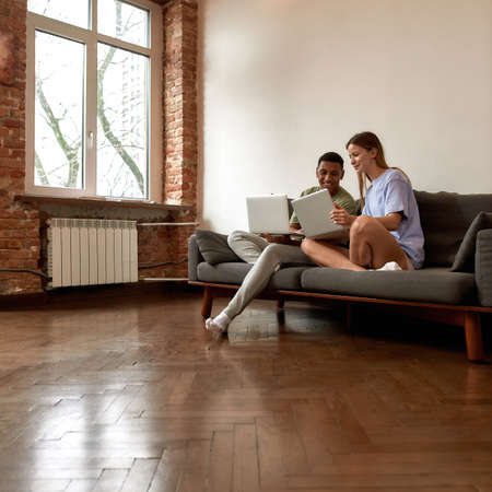 Multiethnic couple looking on laptop of each otherの写真素材