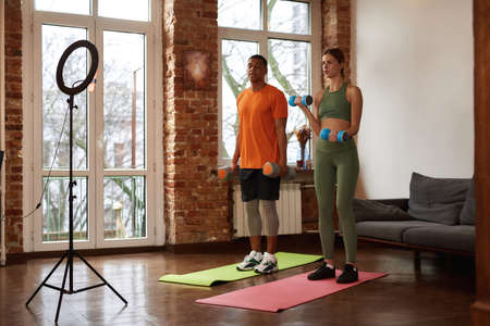 Couple do exercise with dumbbells for sport videoの写真素材