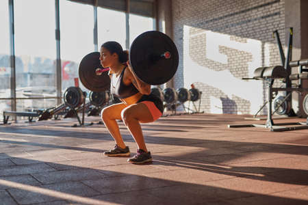 Girl doing sit ups with barbell in sports centerの写真素材