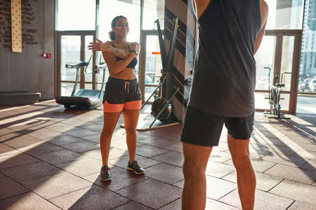 Black girl stretching with trainer in gym