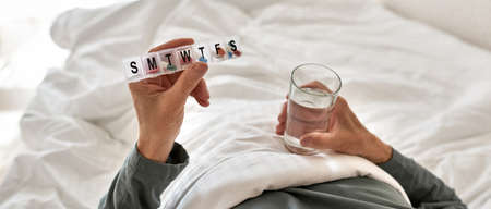 Man holding smtwtfs pills and glass with water