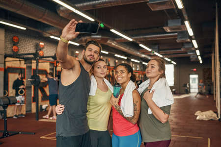 Girls and male trainer take selfie on smartphoneの写真素材