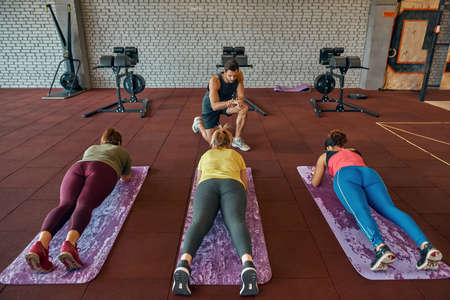 Trainer watching time while girls doing plank