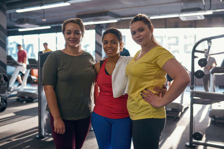 Girls hugging and looking at camera in gymの写真素材