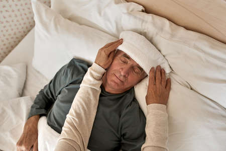 Woman putting towel on forehead of husband on bedの写真素材