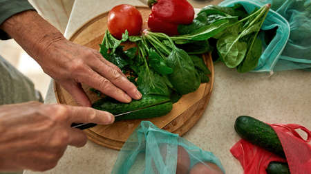 Partial of mature man cutting cucumber with knifeの写真素材