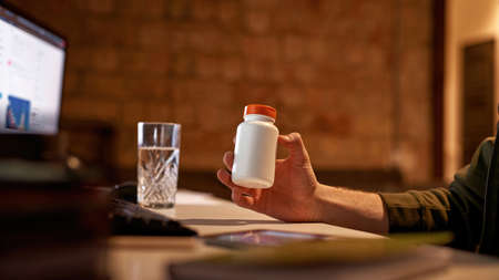 Cropped of male trader holding jar with pillsの写真素材