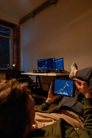 Investor watching chart on digital tablet on sofa