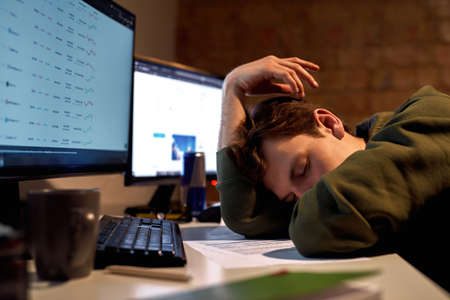 Tired male trader or broker sleeping at tableの写真素材