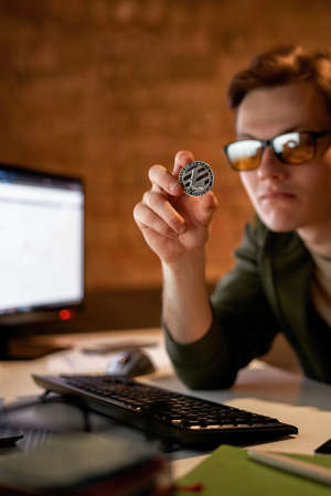 Young male trader investor showing crypto coin