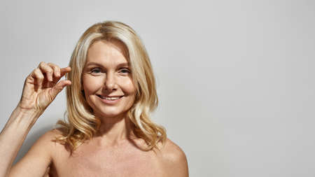 Smiling mature woman hold and show medical pillの写真素材