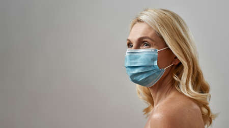 Mature caucasian woman wear medical mask look away