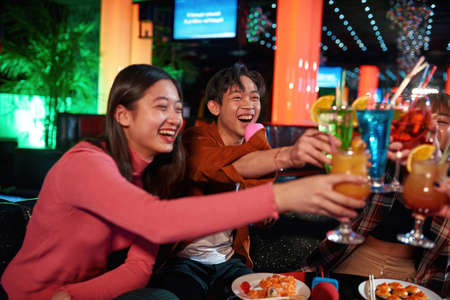 Young asian people cheering and laughing together at nightclub