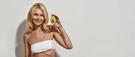 Mature cwoman holding sliced ripe organic avocado
