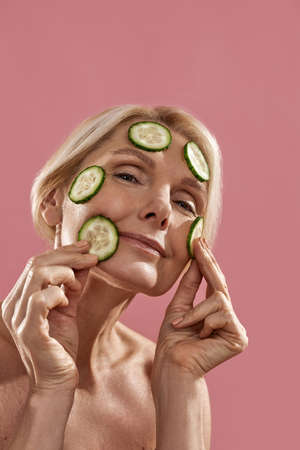 Cropped of woman applying cucumber slices on faceの写真素材