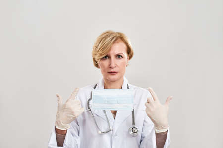 Mature female doctor hold and show medical mask