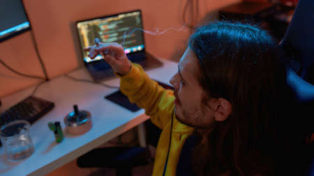 Male IT developer smoke cigarette at work at home