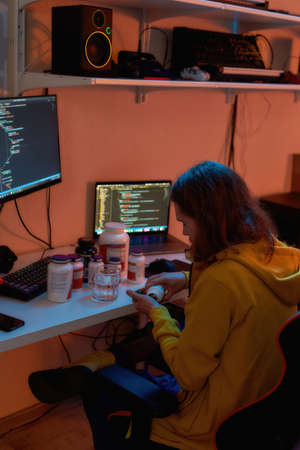 IT developer take medicine pills from jar at homeの写真素材
