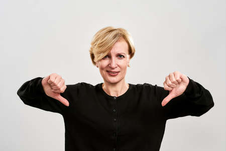 Displeased middle aged woman showing thumbs downの写真素材