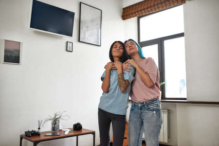 Attractive young women dancing and singing together at home
