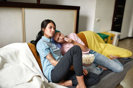 Two young girls watching TV at their homeの写真素材