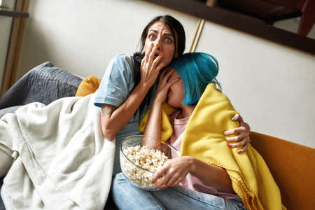 Lesbian women watching scary movie togetherの写真素材