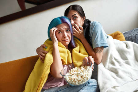 Scared girls on sofa under yellow plaidの写真素材