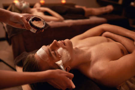 Partial of beautician applying cream on man faceの写真素材