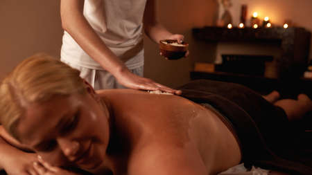 Female masseur smear salt on woman back at scrubの写真素材