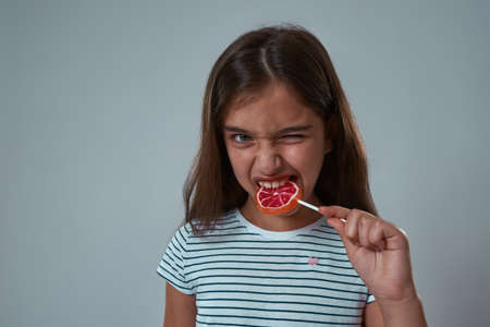 Little girl with face expression biting lollipop