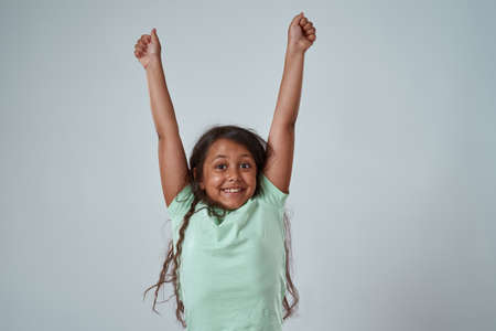 Happy little girl with hands in air celebrate winの写真素材