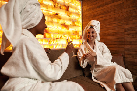 Women drinking champagne and talking in spa salonの写真素材
