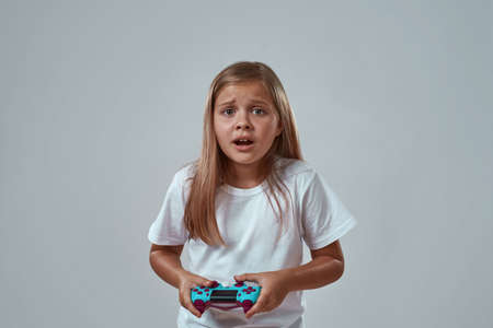 Upset little girl playing video game with joystick