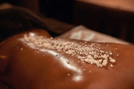 Woman back with salt during scrub in spa salonの写真素材