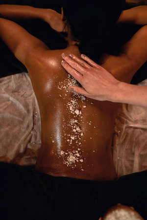 Top view of masseur smearing salt on back of womanの写真素材