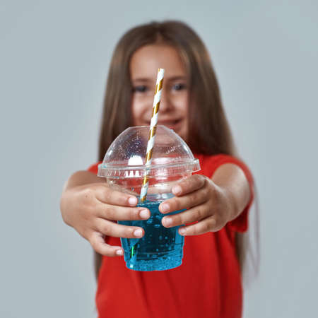 Cup with soda drink in hands of blur little girl