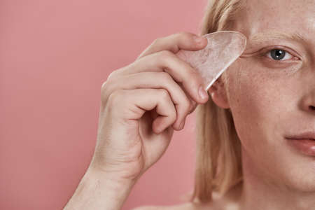 Partial of caucasian guy apply ice slice on faceの写真素材