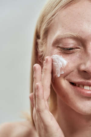 Obscure face of caucasian guy smear cream on faceの写真素材