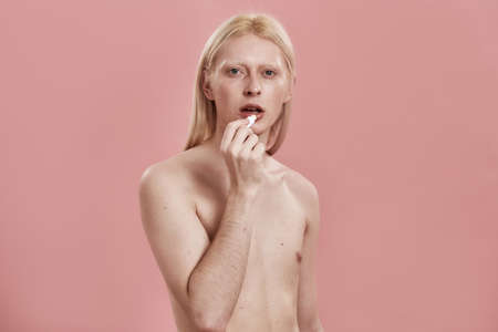 Front view of caucasian guy with hygienic lipstickの写真素材