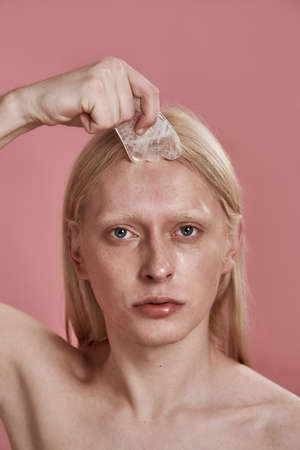 Portrait of guy applying ice slice on his faceの写真素材