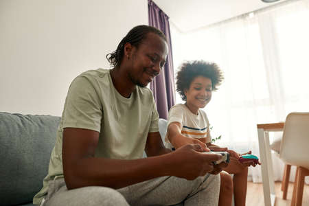 Smiling black boy push button on dad joystick