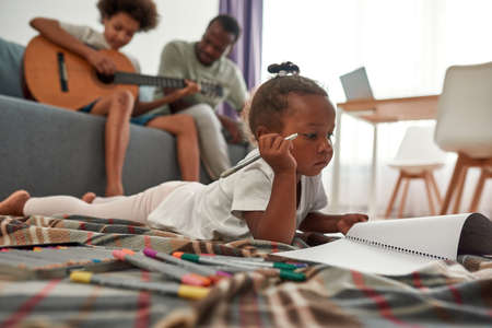 Girl draw while father teach son play on guitarの写真素材
