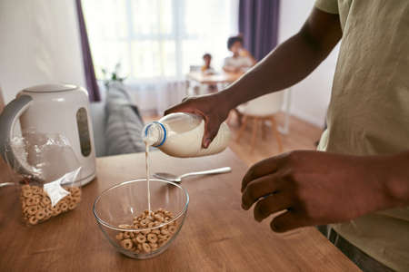 Partial of man pouring milk in bowl with cereals